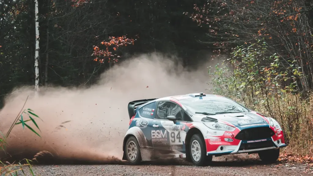 Ralliauto kihutamas kruusateel, tõstes õhku paksu tolmu ja kruusakive.