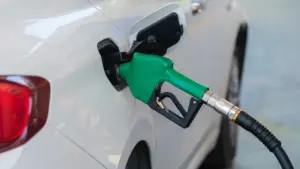 Auto tankimine bensiinijaamas, roheline tankimispüstol on sisestatud valge auto kütusepaaki.